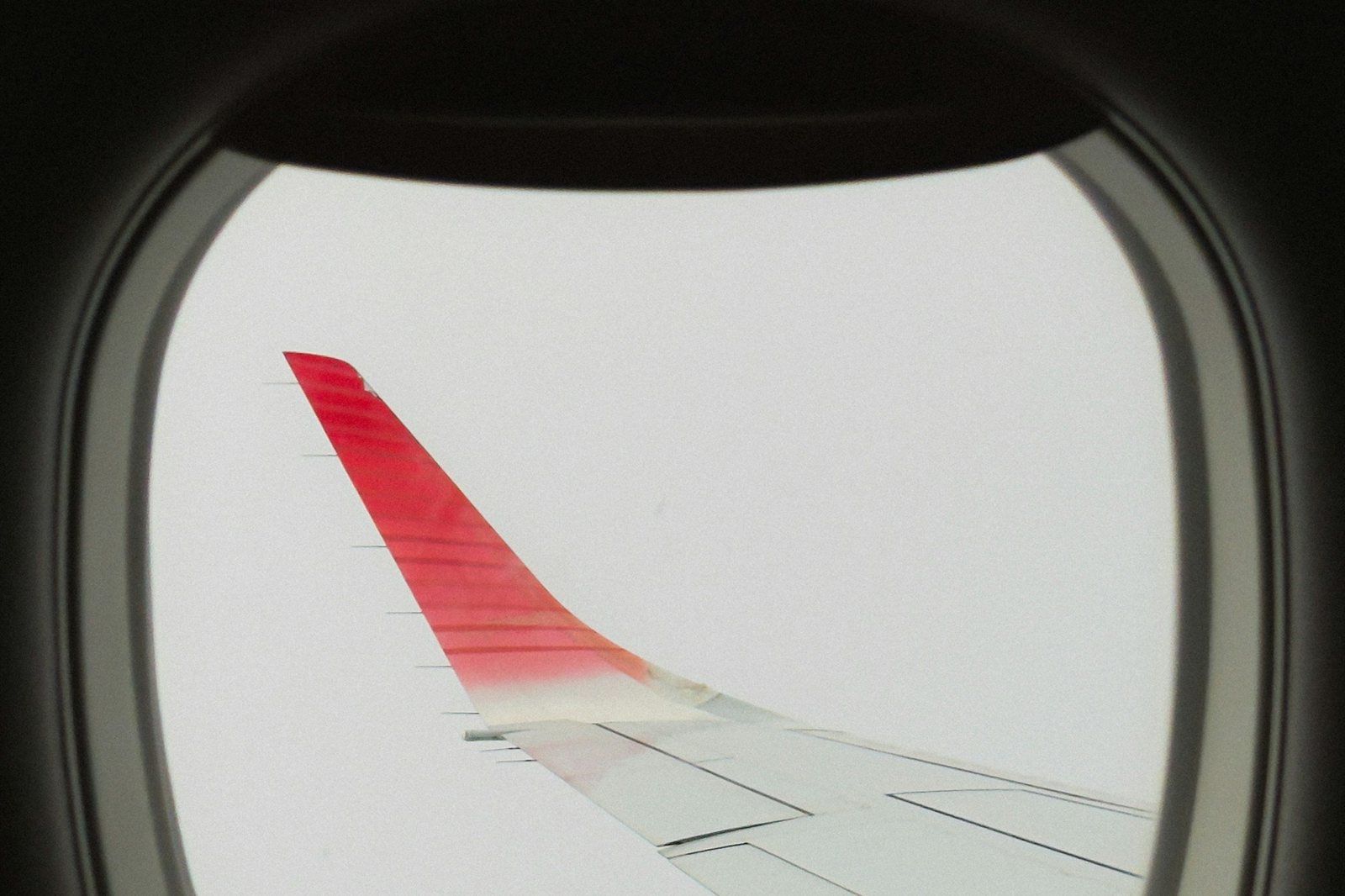 The view of an airplane wing through a cabin window during a direct flight