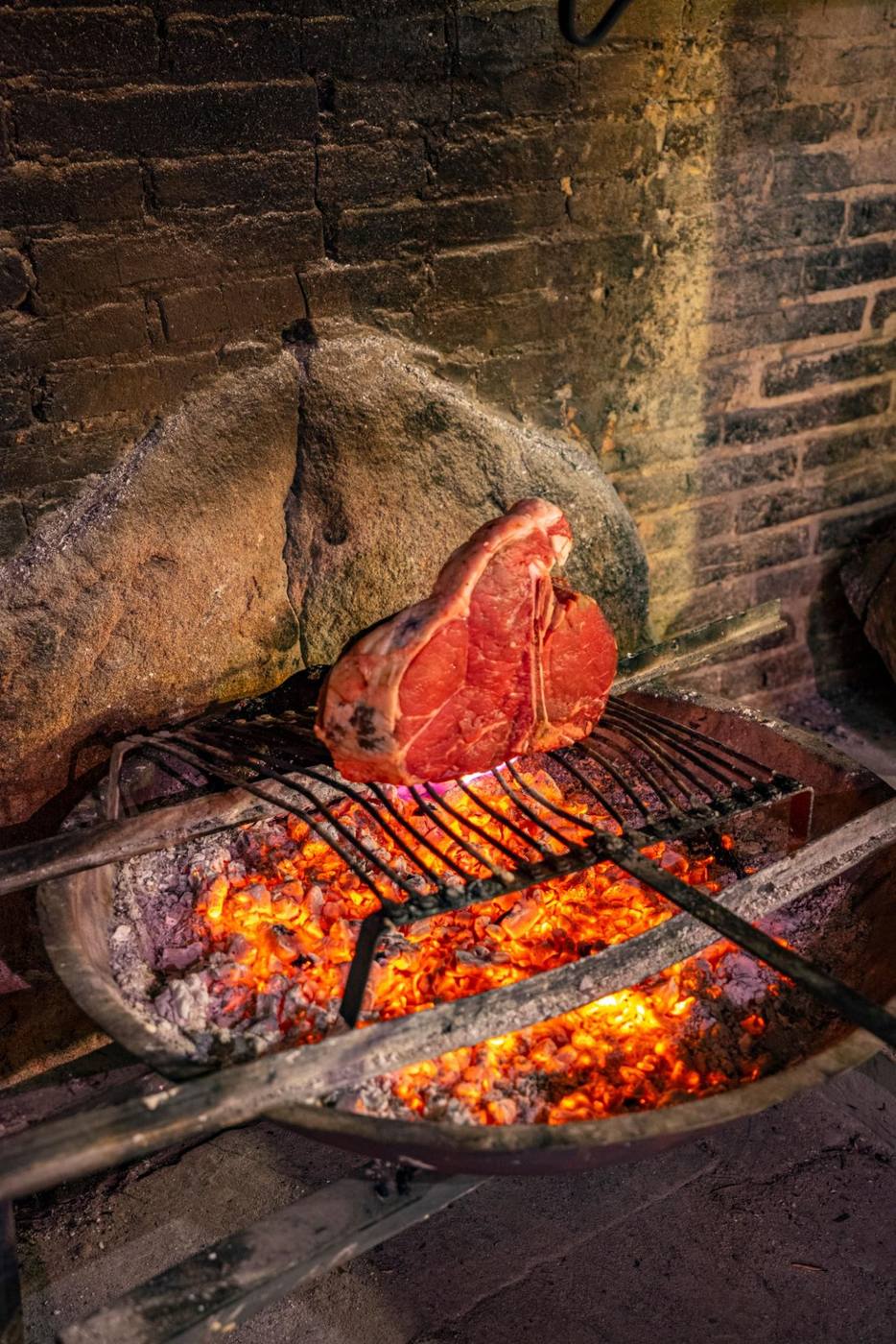 Bistecca alla fiorentina grilling over an open fire in Tuscany